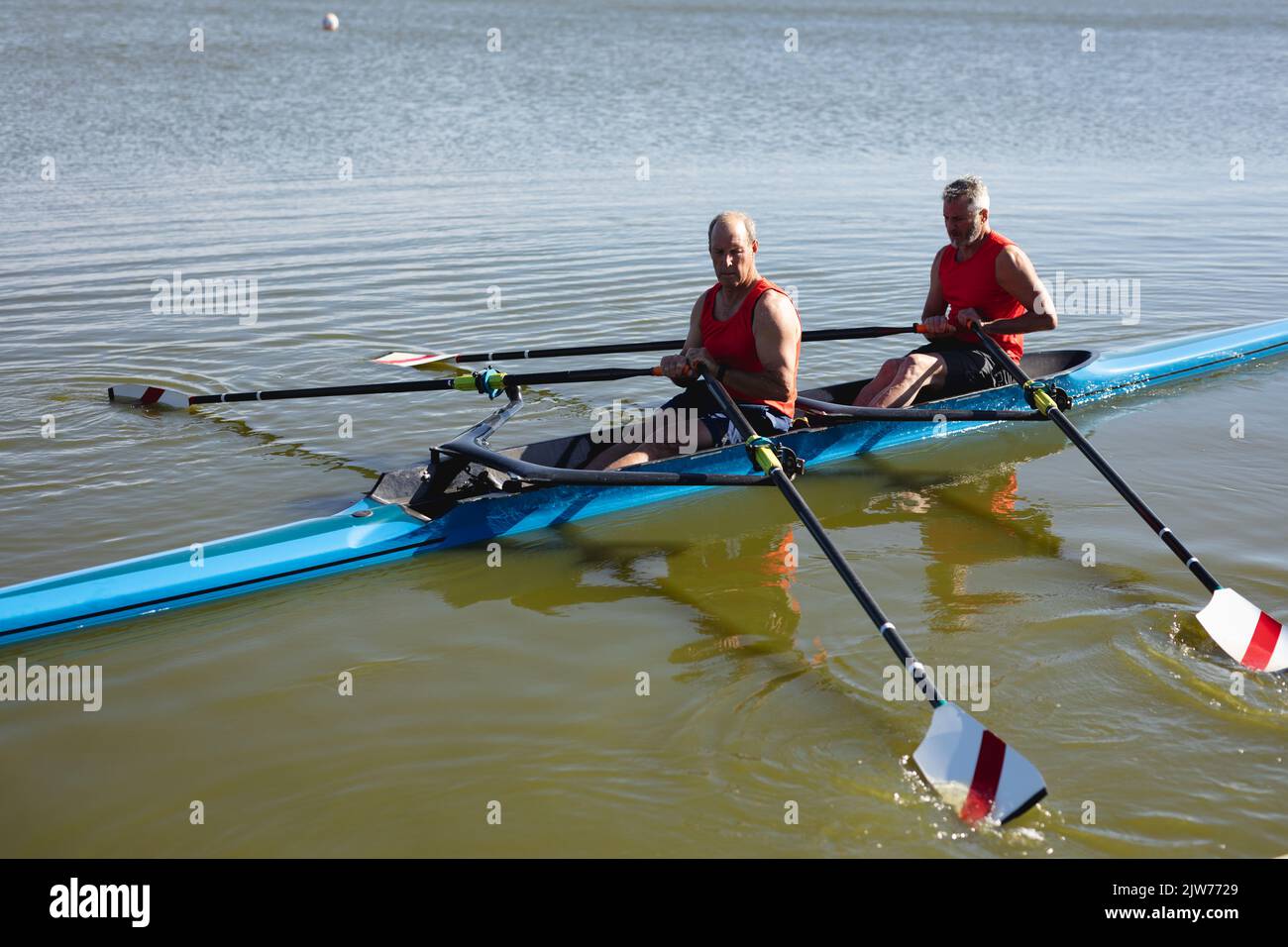 Two senior caucasian male rowers rowing the boat on the lake Stock