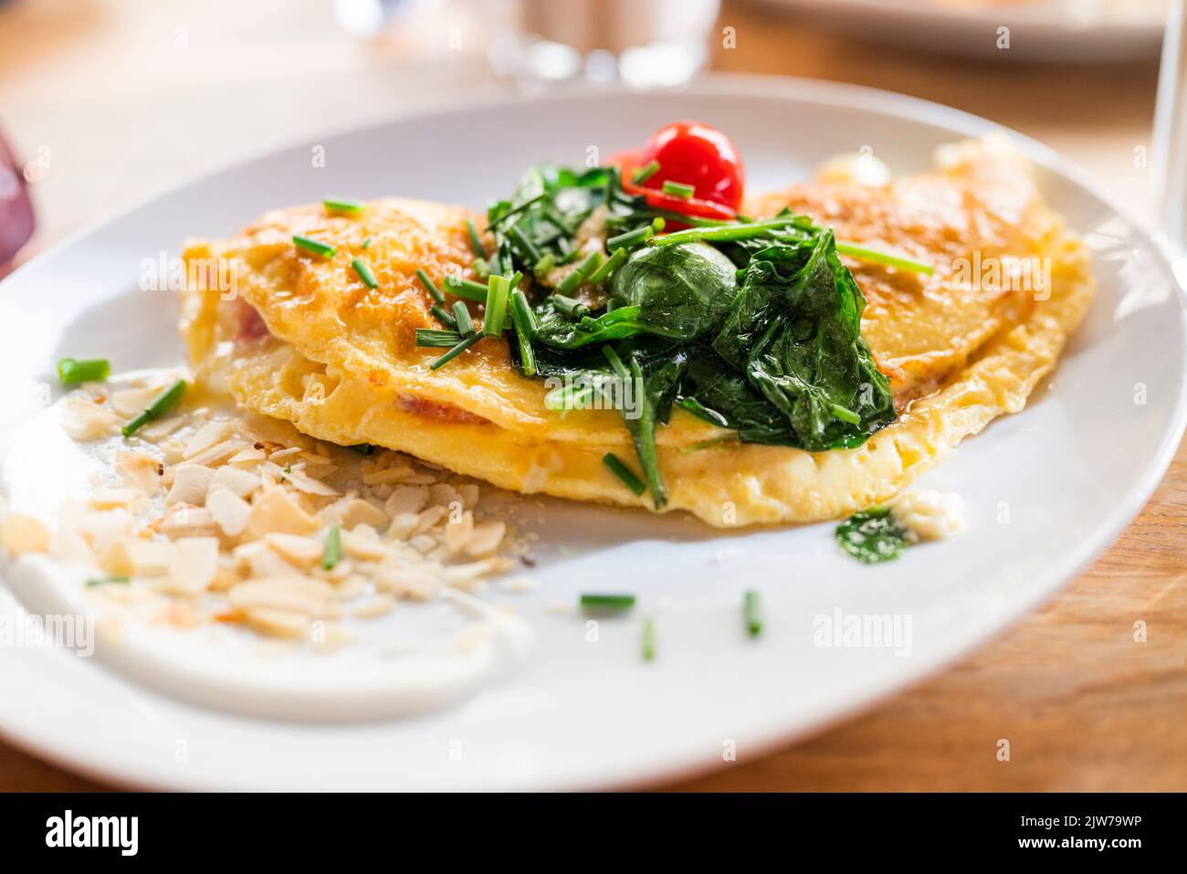 breakfast scrambled eggs with vegetables and spinach on a plate in a restaurant Stock Photo