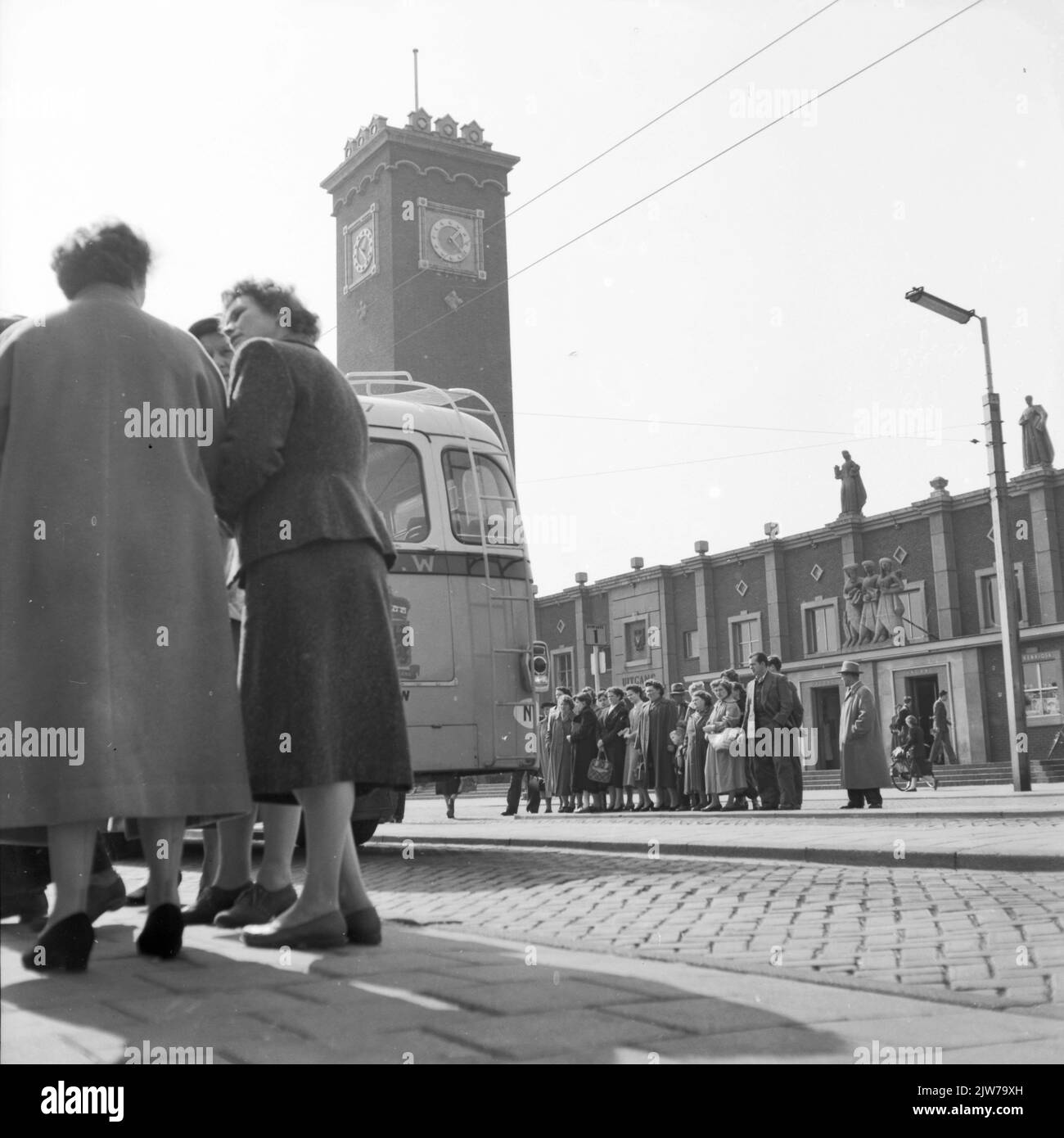 Image of waiting people on the bus station on Stationsplein in Nijmegen. In the background the N.S. station Nijmegen. Stock Photo