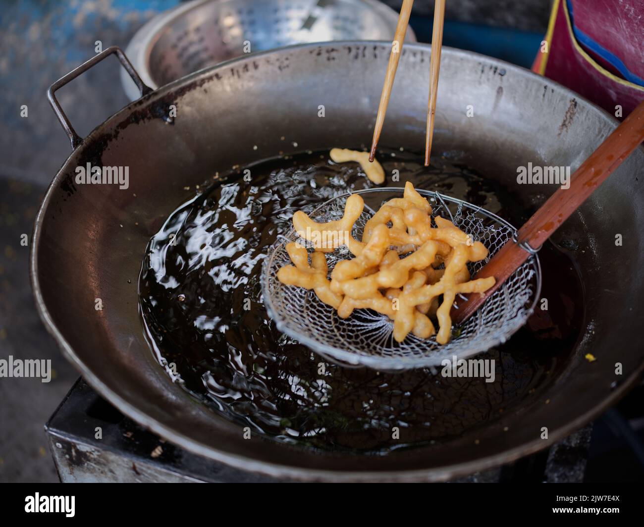 Die cut of Deep fried Chinese Doughnut in an big oil pan Stock Photo
