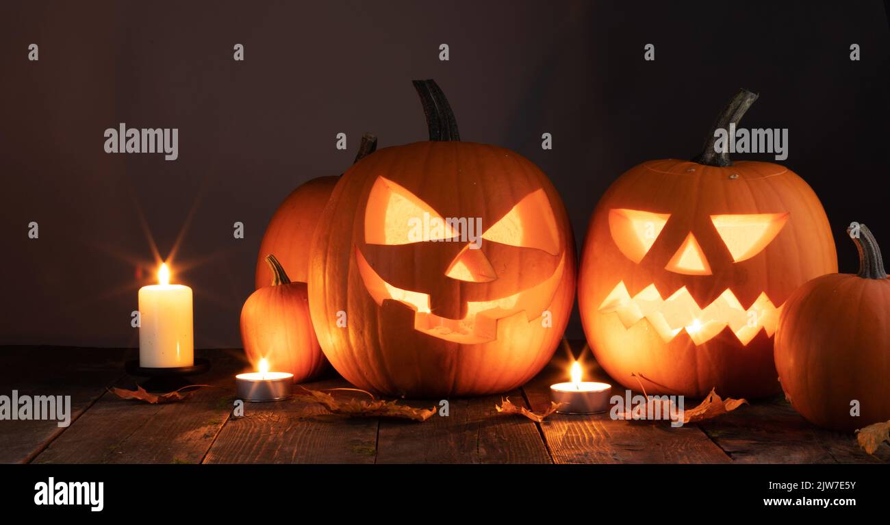 Halloween pumpkins candles and dry maple leaves on wooden background Stock Photo