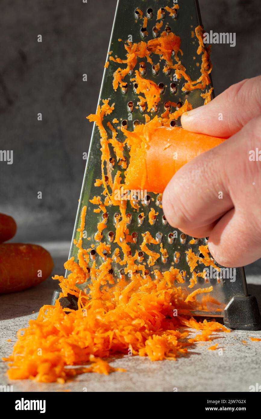 https://c8.alamy.com/comp/2JW7G2X/grating-a-carrot-on-a-stainless-steel-grater-on-a-concrete-background-in-sunlight-2JW7G2X.jpg