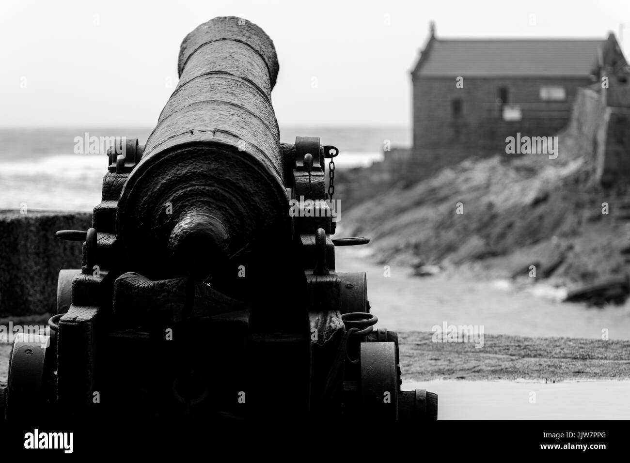 Black and white image of the famous canon at Porthleven harbour. overlook the lifeboat house. Stock Photo