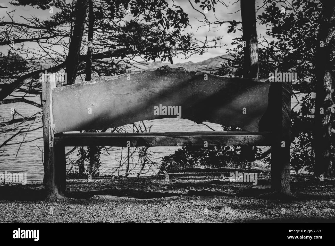 Black and white image of a bench with the perfect view over Penrose National trust lake. Stock Photo