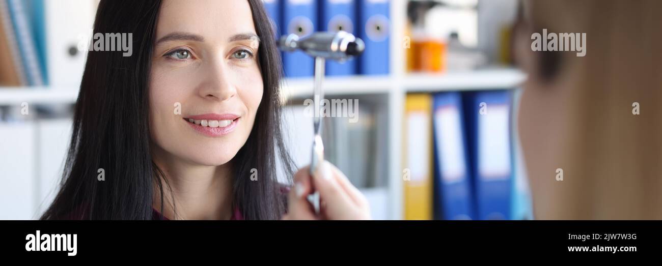 Neurologist driving hammer in front of patient eyes in clinic Stock Photo