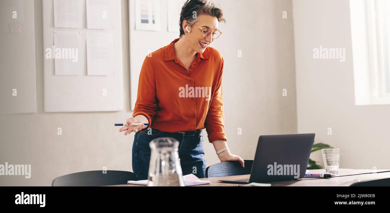Happy businesswoman pitching her idea to a client in an online meeting. Smiling designer discussing her plan during a video call. Mature businesswoman Stock Photo