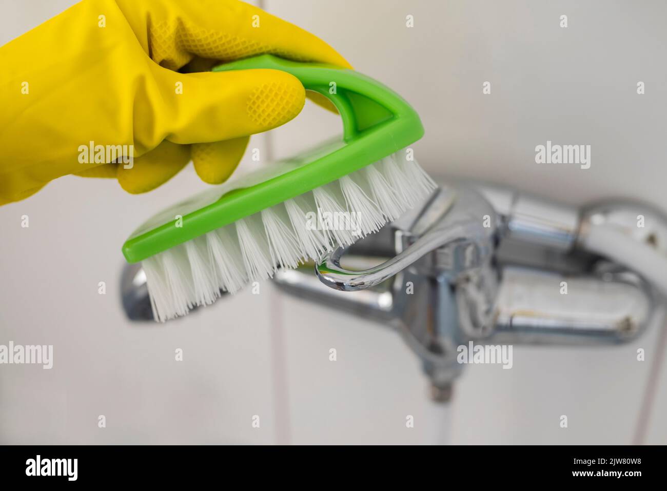 girl in rubber gloves with a brush does cleaning in the bathroom washbasin Stock Photo