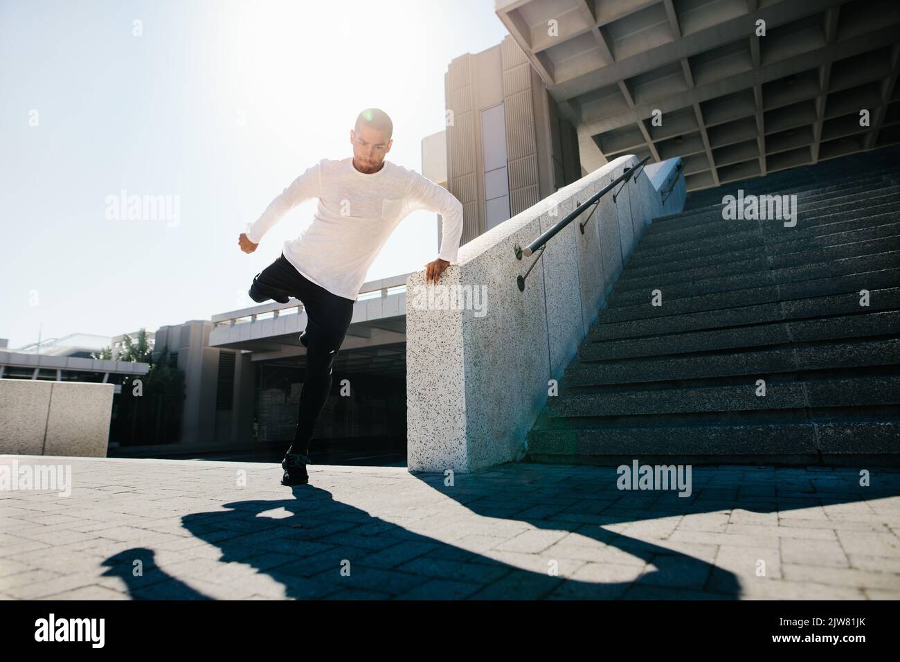 Fit urban guy performing a wall spin outdoors in city. Young sportsman practicing parkour and free running. Stock Photo