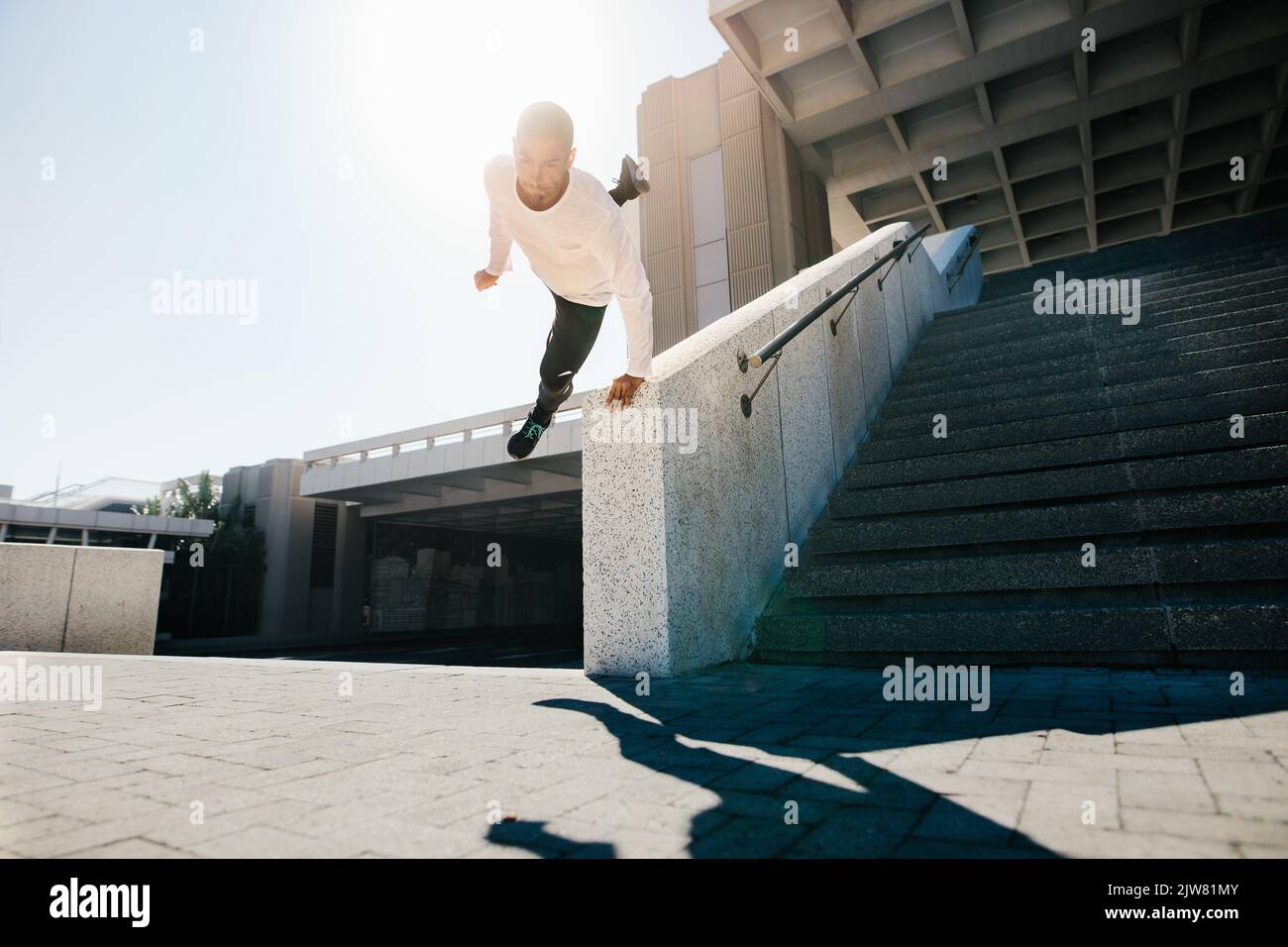 Urban free runner doing a wall spin. Young sportsman practicing parkour and free running outdoors. Parkour in an urban space. Stock Photo