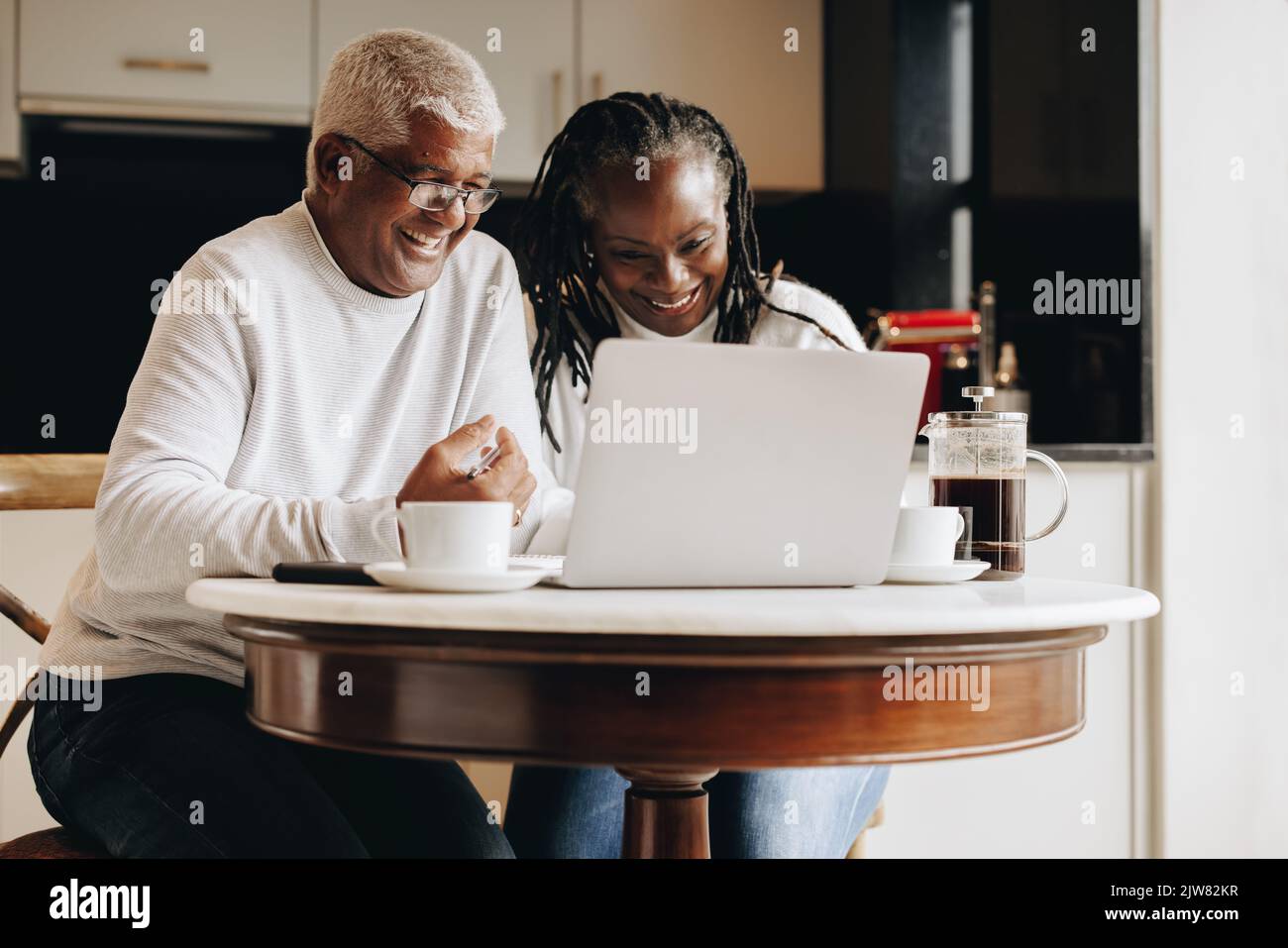 Cheerful senior couple having a video call on a laptop at home. Mature couple having a virtual meeting with a retirement consultant. Happy senior coup Stock Photo