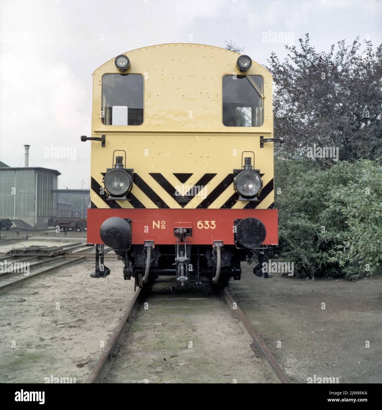 Image of the diesel-electric shunting locomotive no. 633 (series 600) of the N.S. In yellow version and with shock stripes at the main workshop of the N.S. in Tilburg. Stock Photo