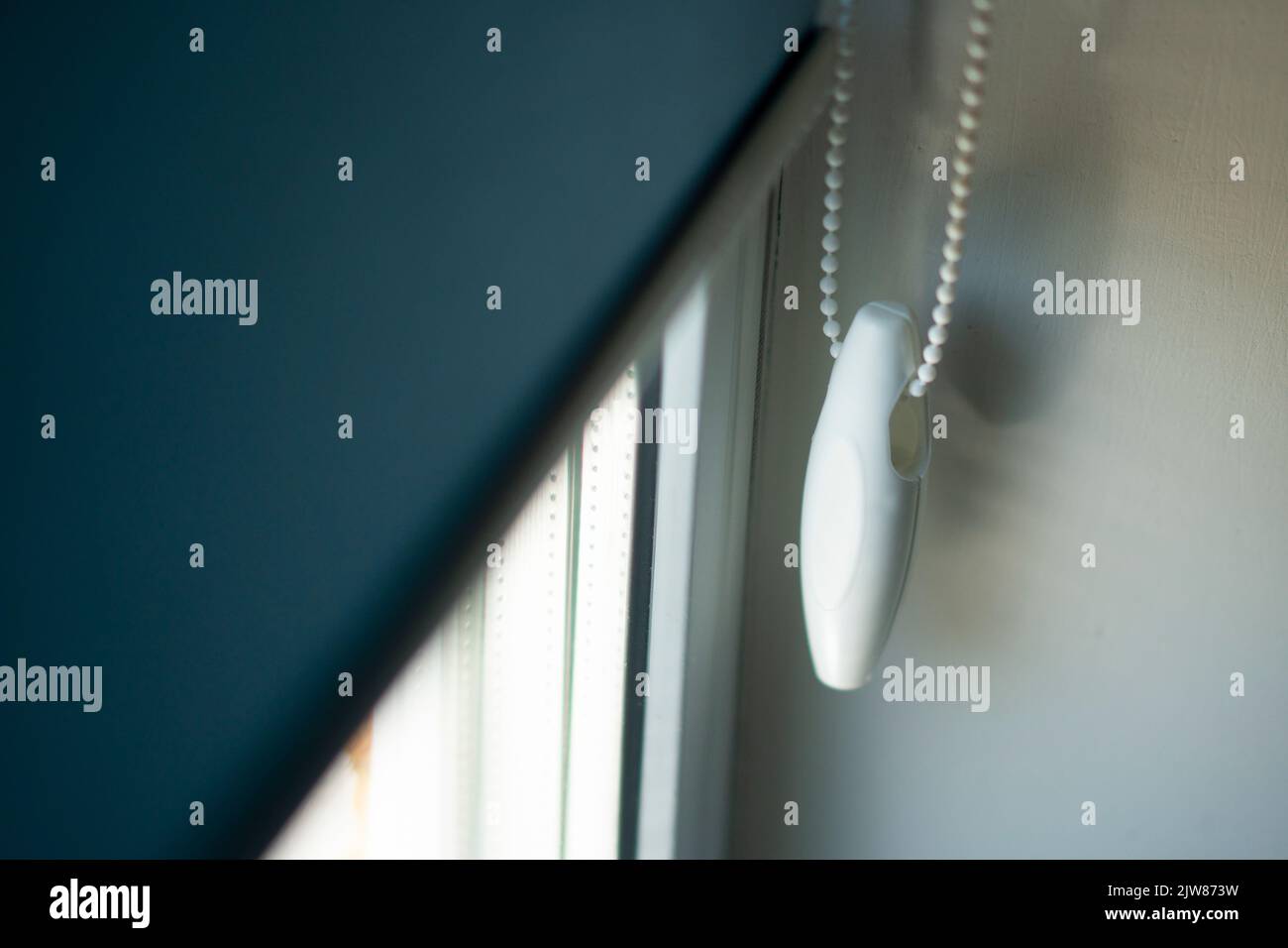 handle for lowering fabric roller blinds on a metal-plastic window. Stock Photo