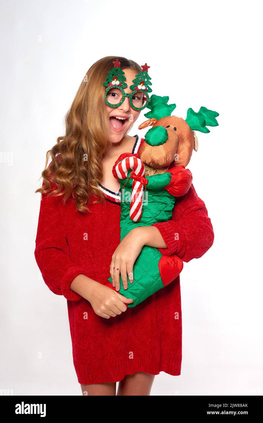 happy girl in Christmas costume holds toy sock in form of santa deer in hands and fools around Stock Photo