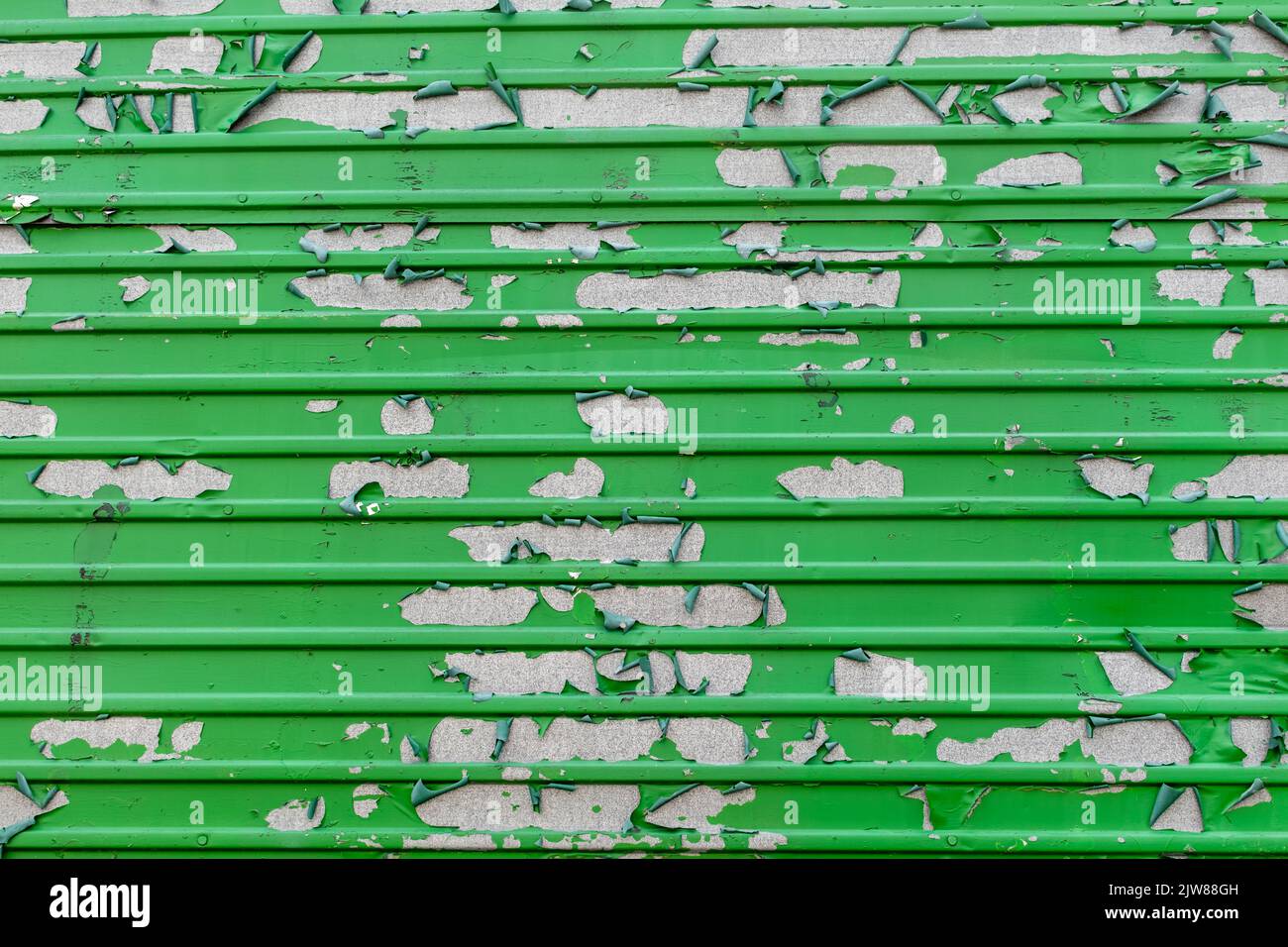 Peeling green paint in messy pattern on corrugated metal surface Stock Photo