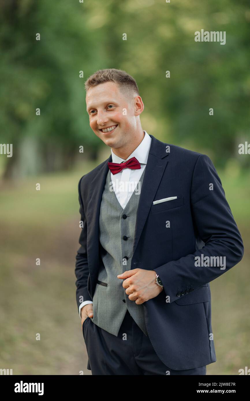 Vertical portrait laughing, confident handsome smiling blond businessman or groom in formal wear in natural parkland Stock Photo