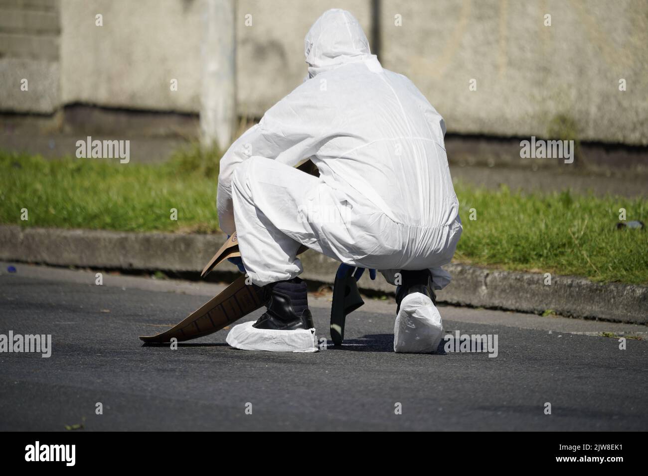 Forensic officers remove a shoe from the scene in the Rossfield Estate