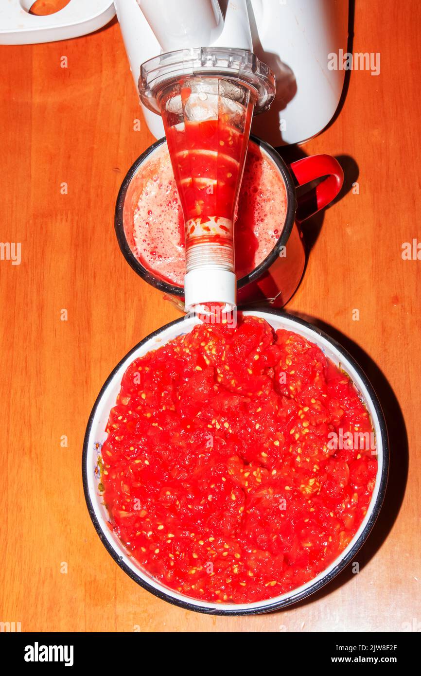 A woman prepares fresh healthy juice from tomatoes. Juicer at work