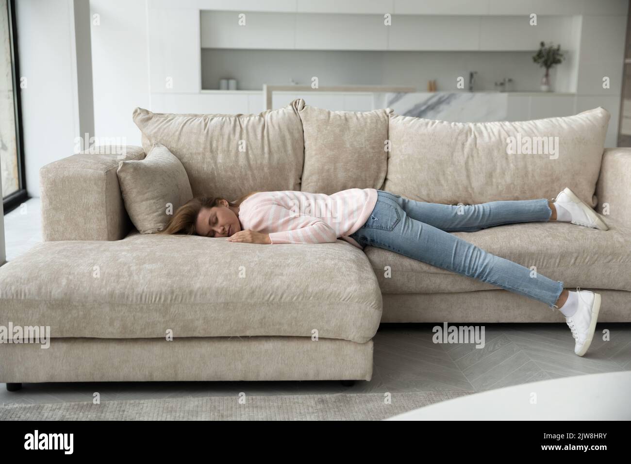 Sleeping young woman resting on home couch full length shot Stock Photo