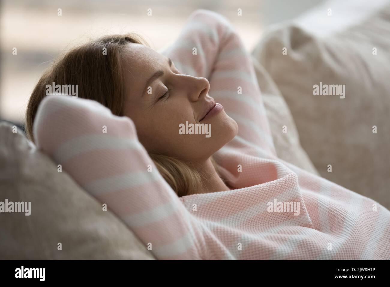 Calm sleepy Caucasian woman relaxing on soft couch Stock Photo