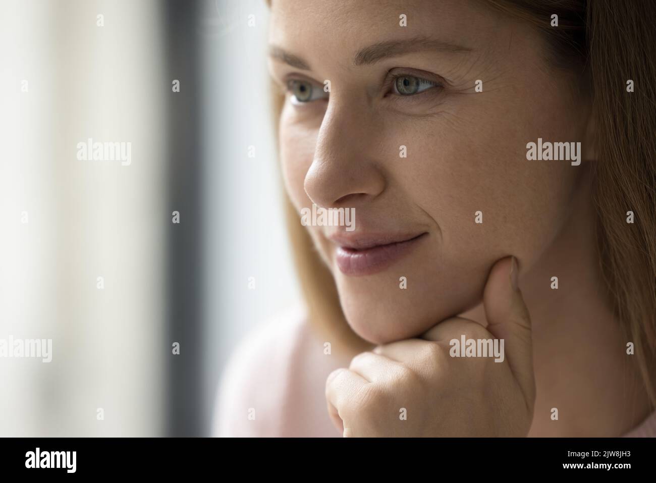 Happy thoughtful adult Caucasian woman looking at window Stock Photo