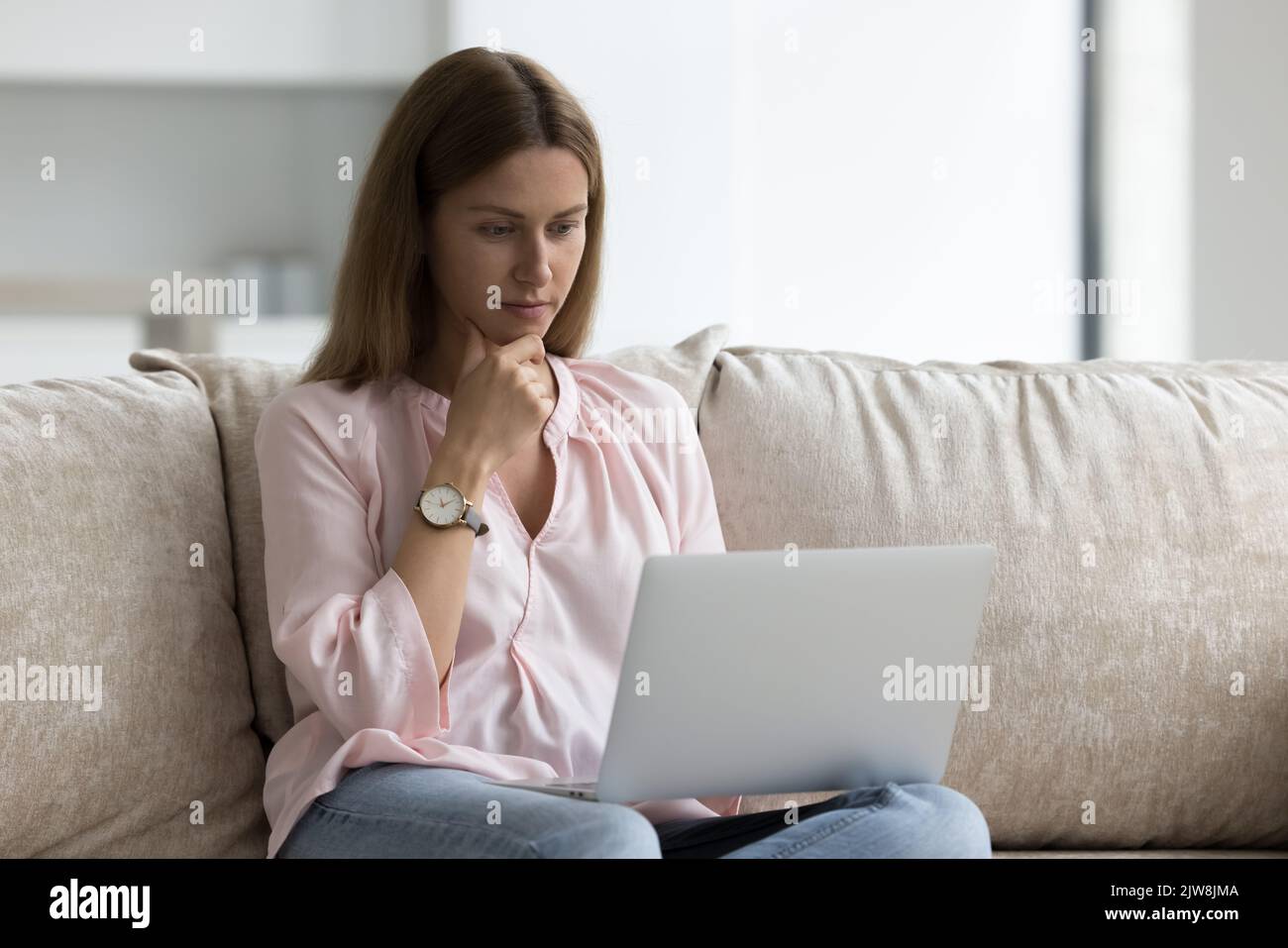 Focused young Caucasian freelance business woman using laptop computer Stock Photo