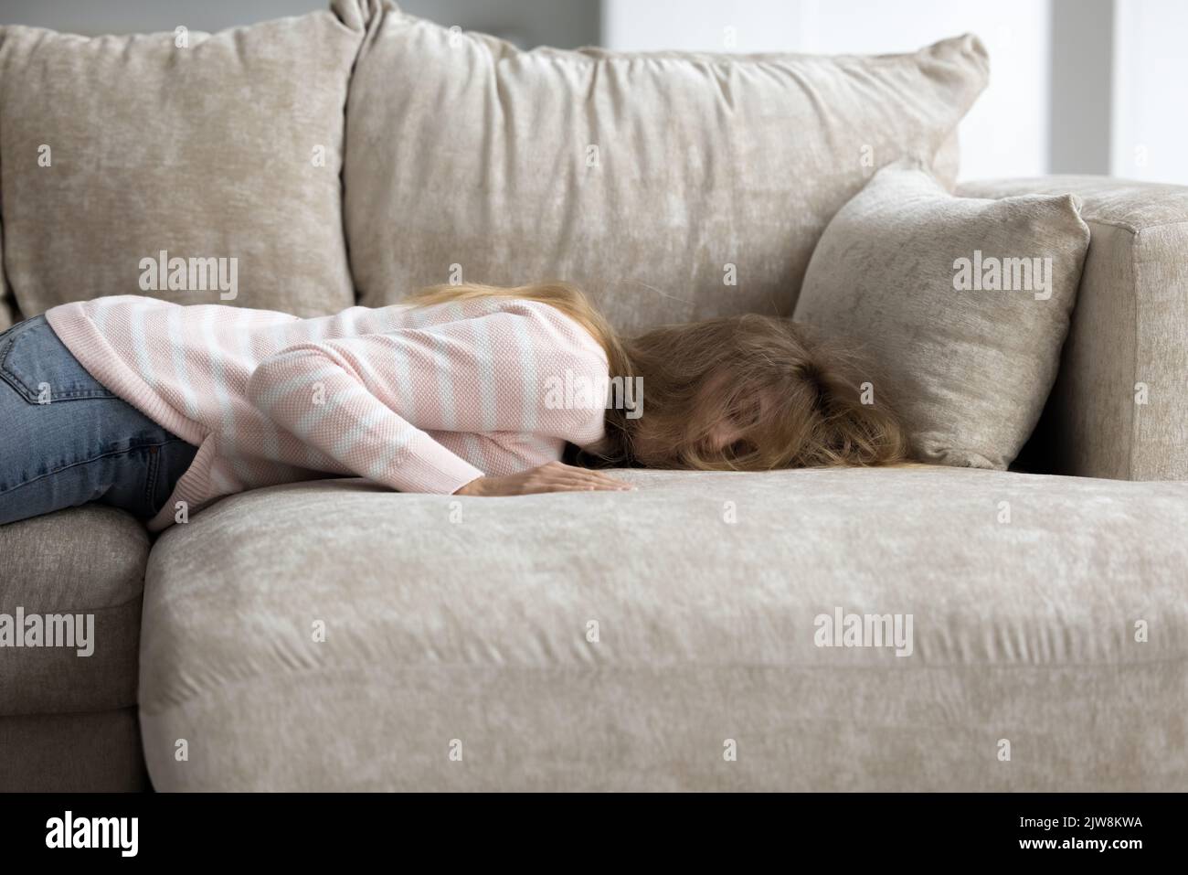 Tired exhausted sleepy young woman lying on belly on couch Stock Photo