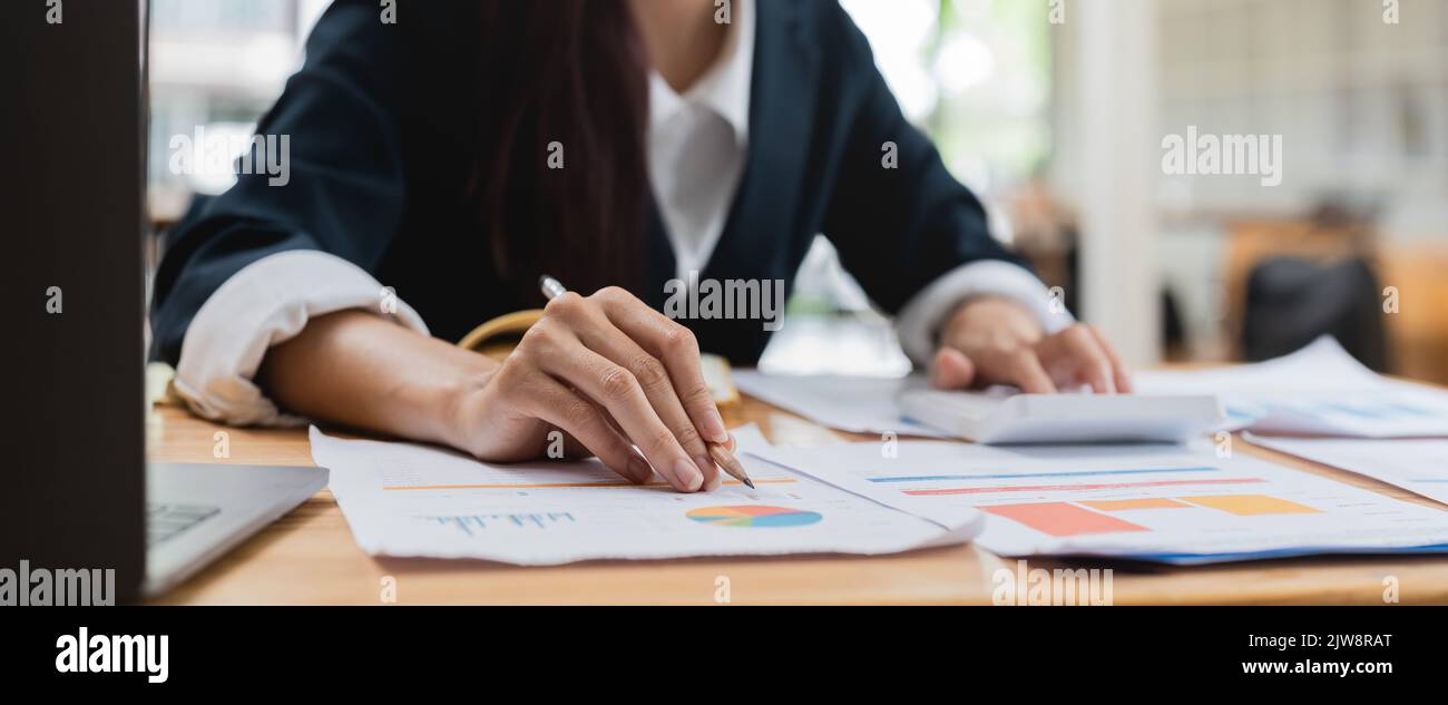 Close up woman hand press calculator to calculate the company's financial results On the wooden table in the office and business work background, tax Stock Photo