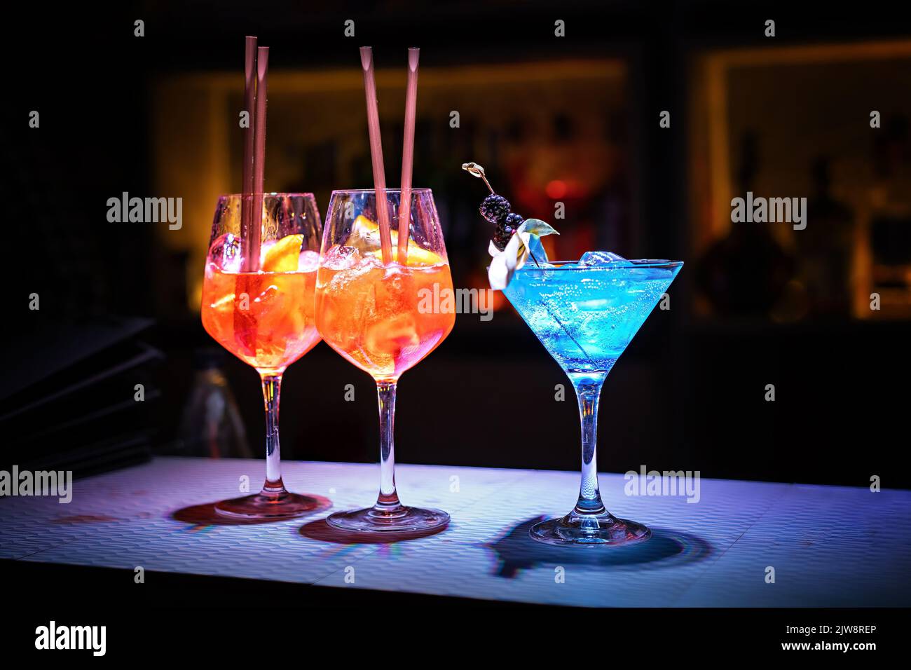 Three glasses with fresh alcohol drinks and with ice cubes on the bar counter of a night club - lifestyle concept Stock Photo