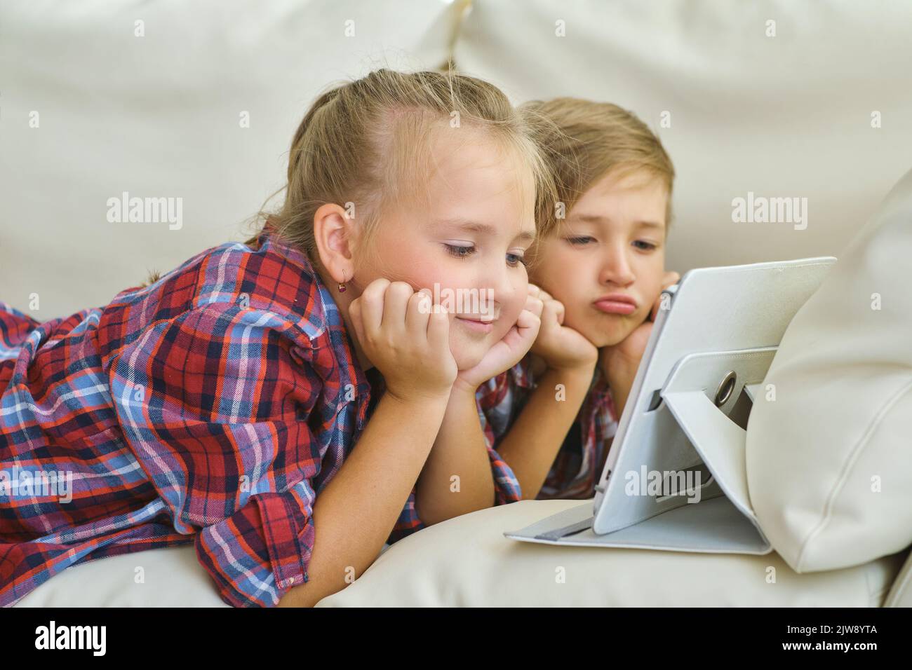 smiling brother and sister with tablet on the sofa in living room Stock ...