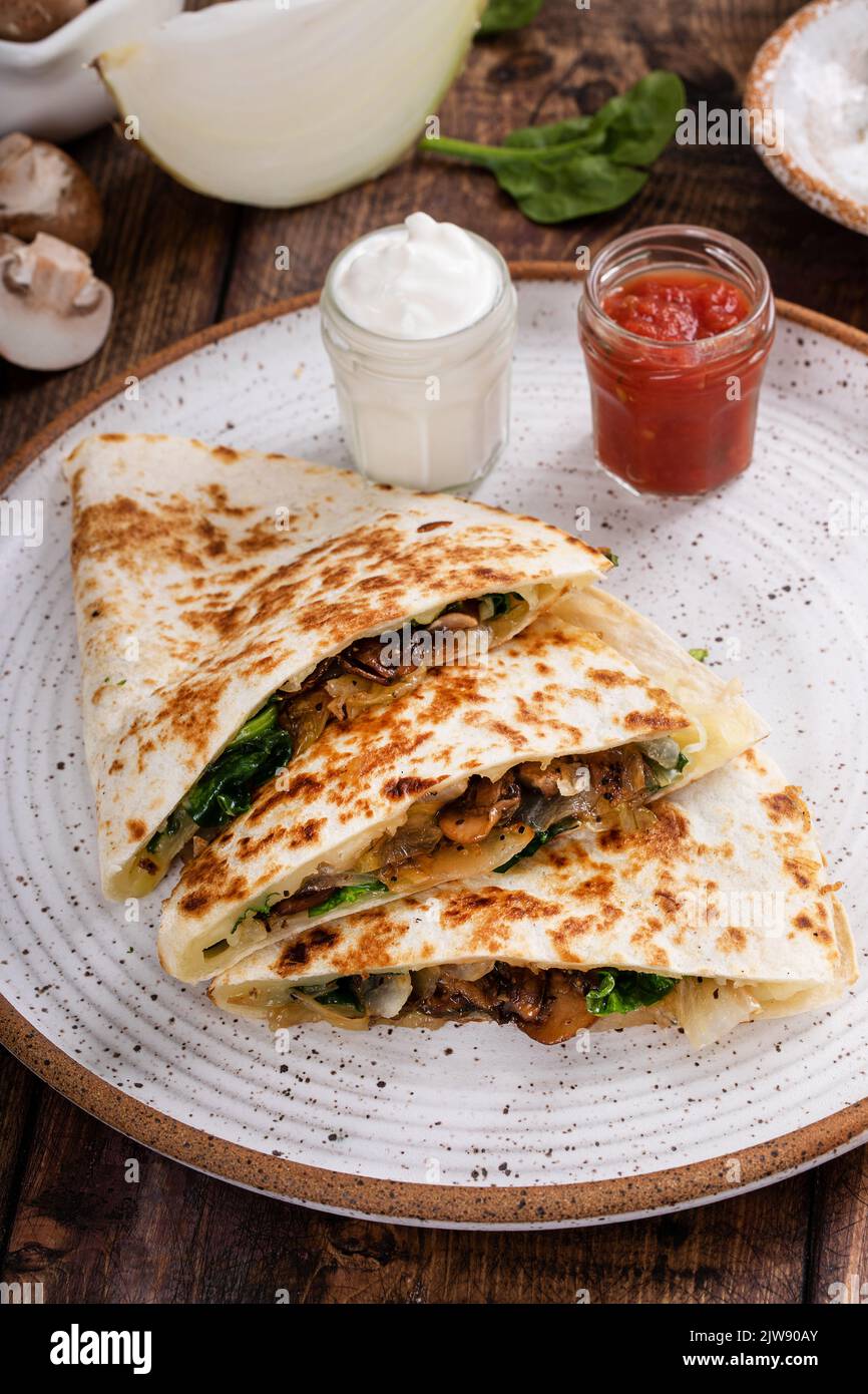 Mushroom and spinach quesadillas with sour cream and salsa Stock Photo