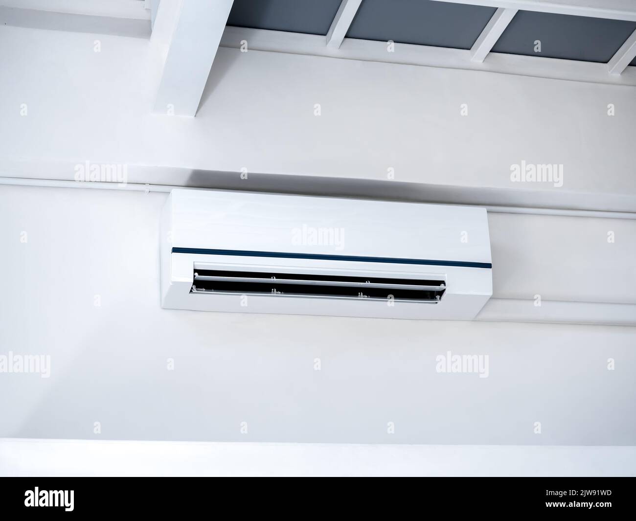 White air conditioner on wall background. Wall mounted air conditioner hanging on white wall under the room structure in clean living room in the hous Stock Photo