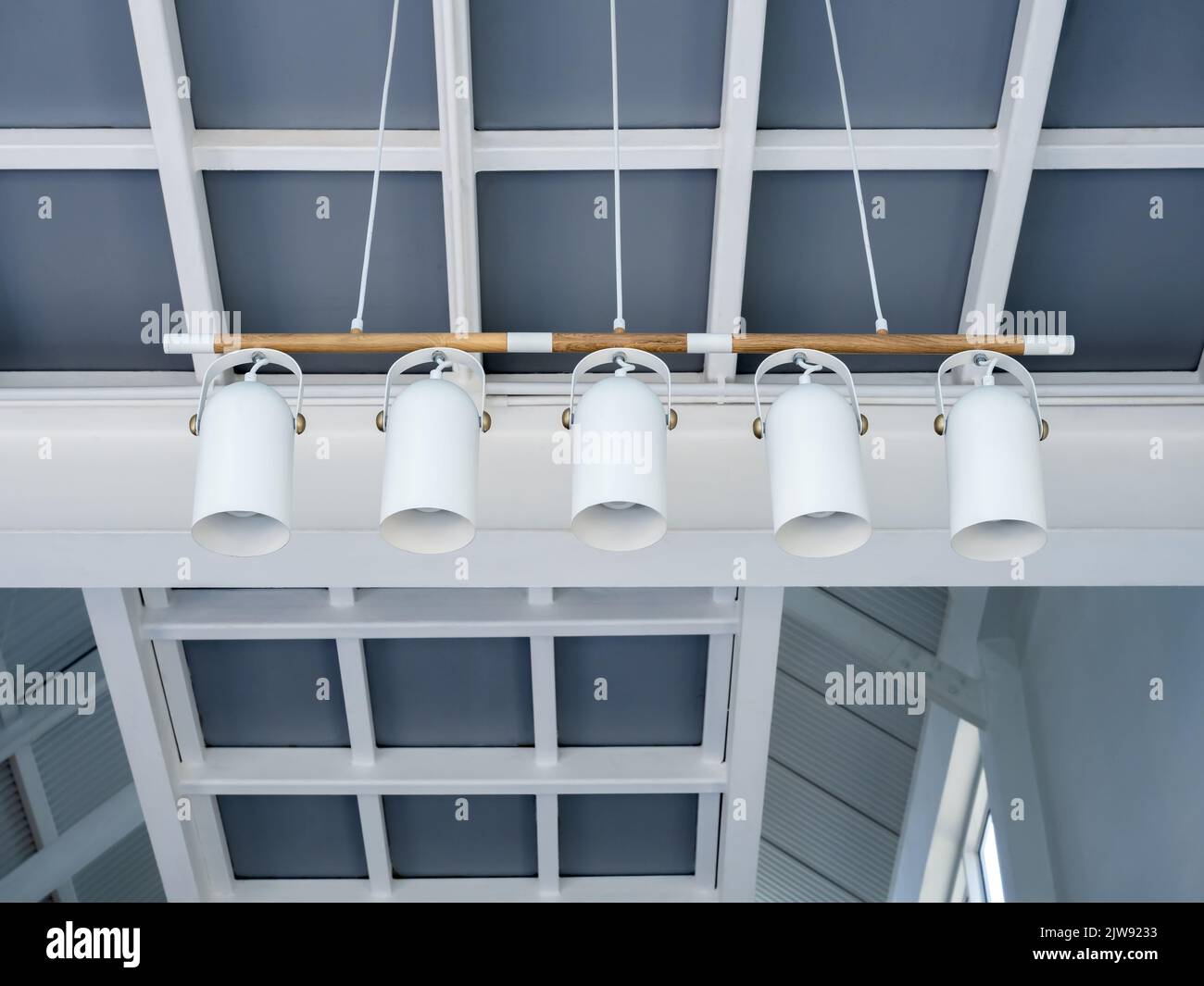 five spotlight hanging  in cafe. Modern ceiling lamps set under the stylish construction building in living room in the white house. Stretch ceiling w Stock Photo