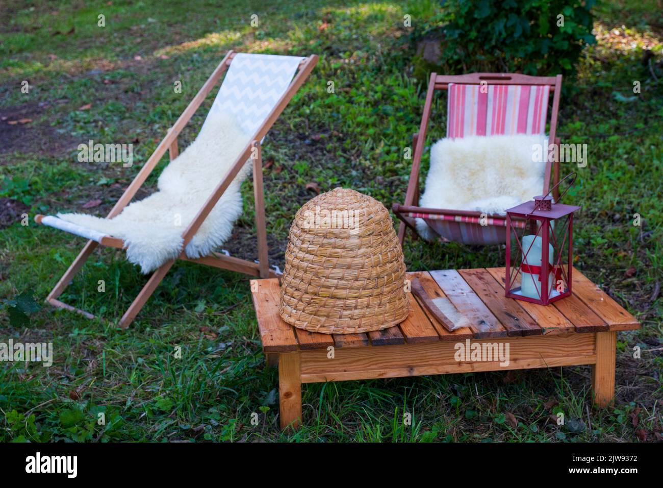Liegestuhl aus Holz im Wald, romantisch mit Bienenkorb Deko Stock Photo