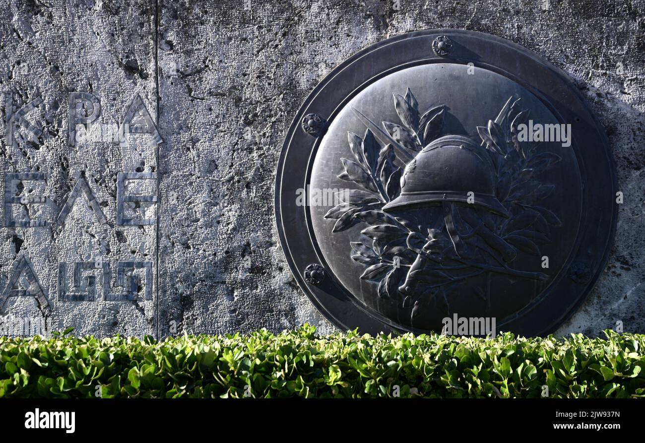 Antique bronze shield against a stone wall with an ancient inscription ...