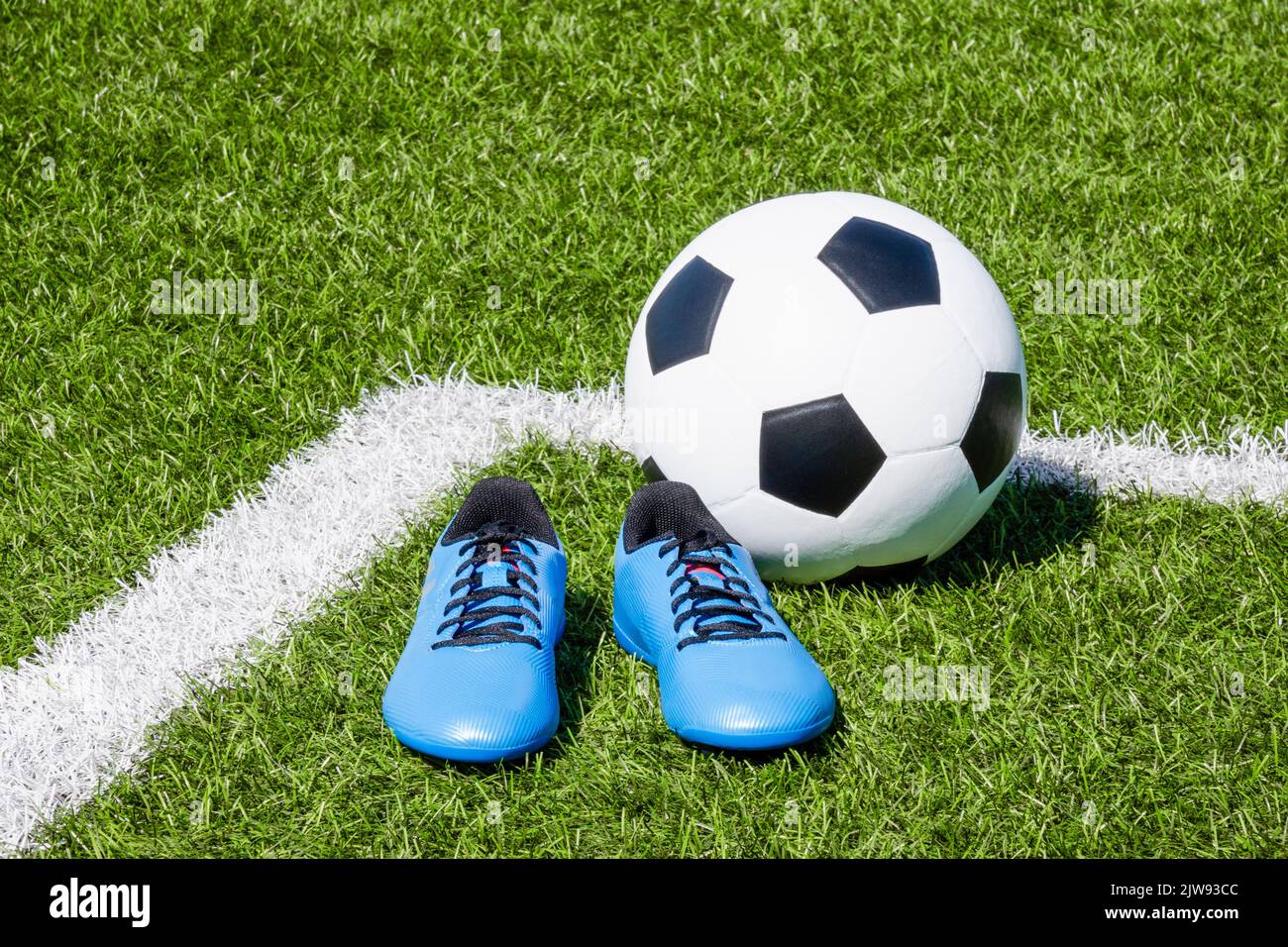 Soccer ball and pair of soccer football sports shoes cleats on green