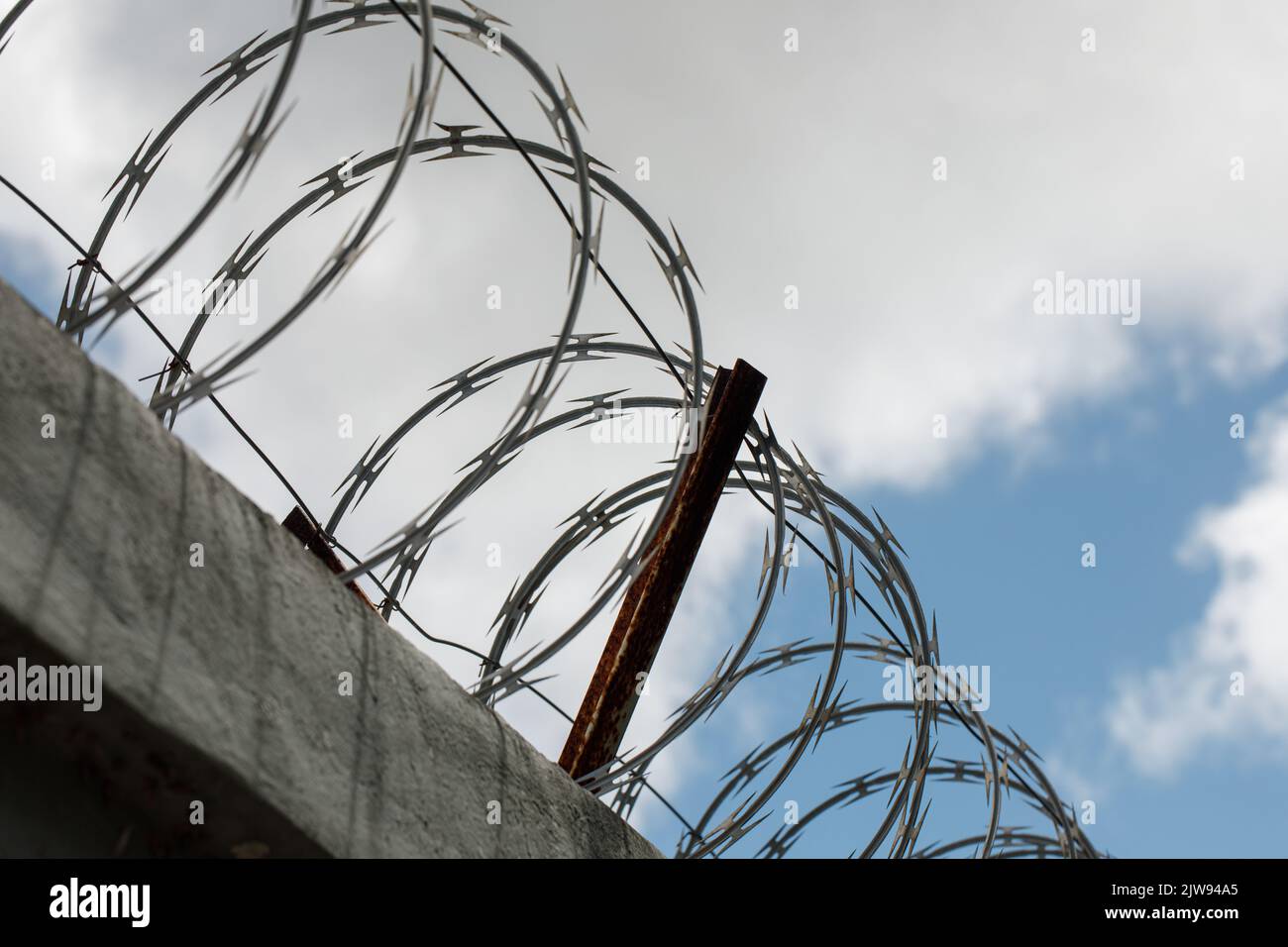 Chain link fence with barbed wire and razor wire. against the blue sky