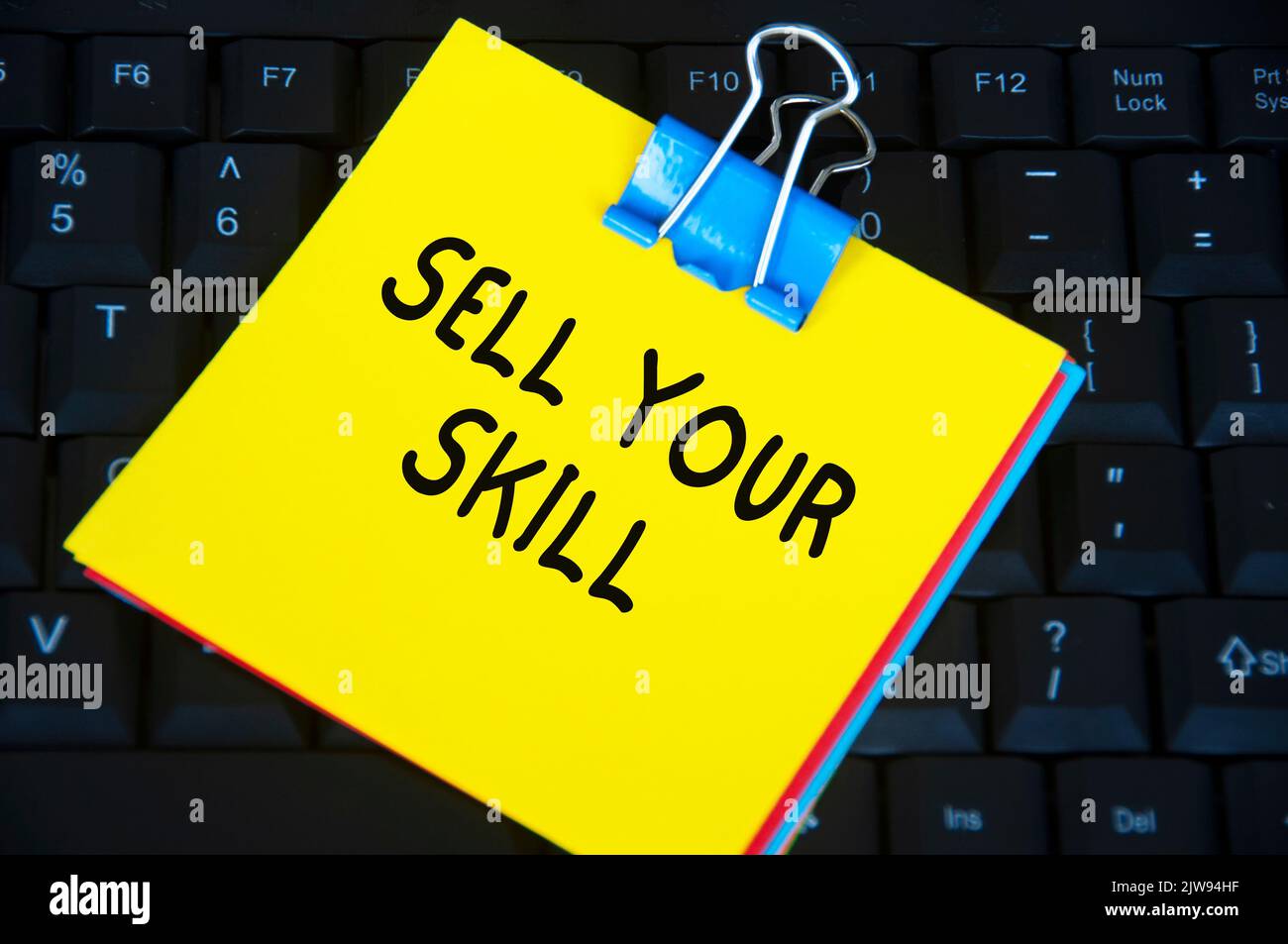 Sell your skill text on yellow notepad on black keyboard background. Stock Photo