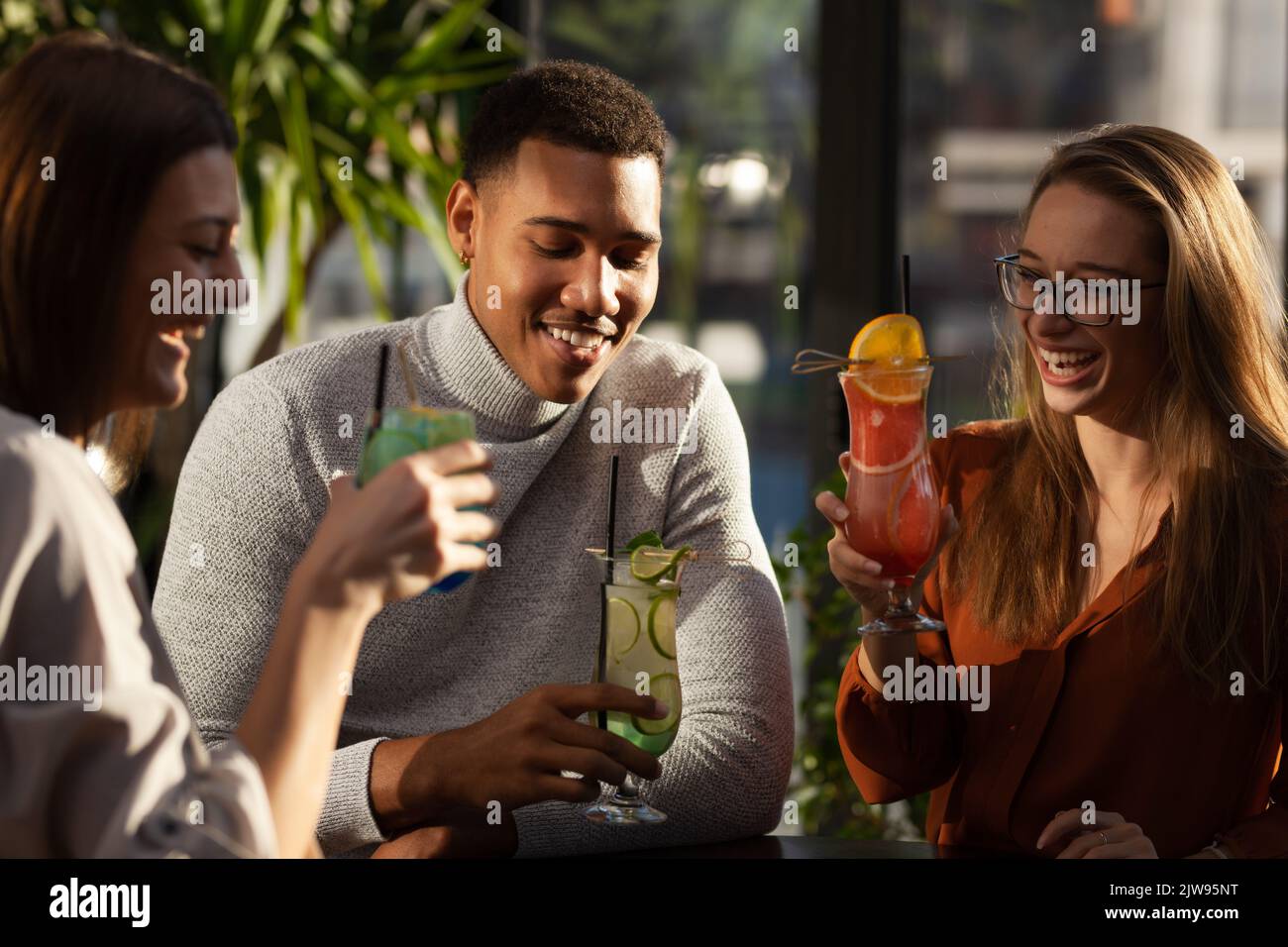Three multiracial friends in a bar cheering. After work party with