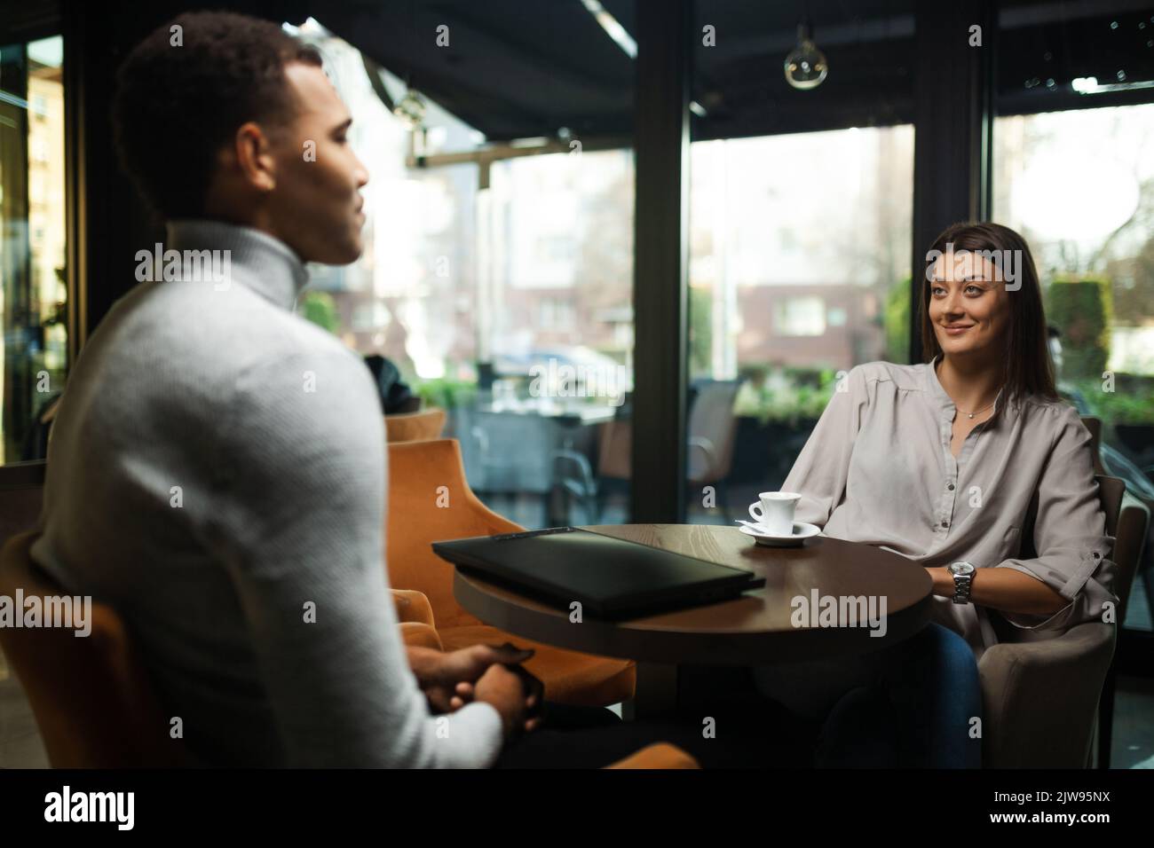 Friends at a cafe after work. Business colleagues working on laptop and drinking coffee in a restaurant. Stock Photo