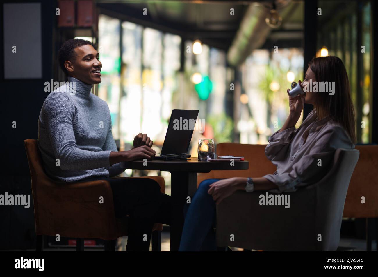 Friends at a cafe after work. Business colleagues working on laptop and drinking coffee in a restaurant. Stock Photo