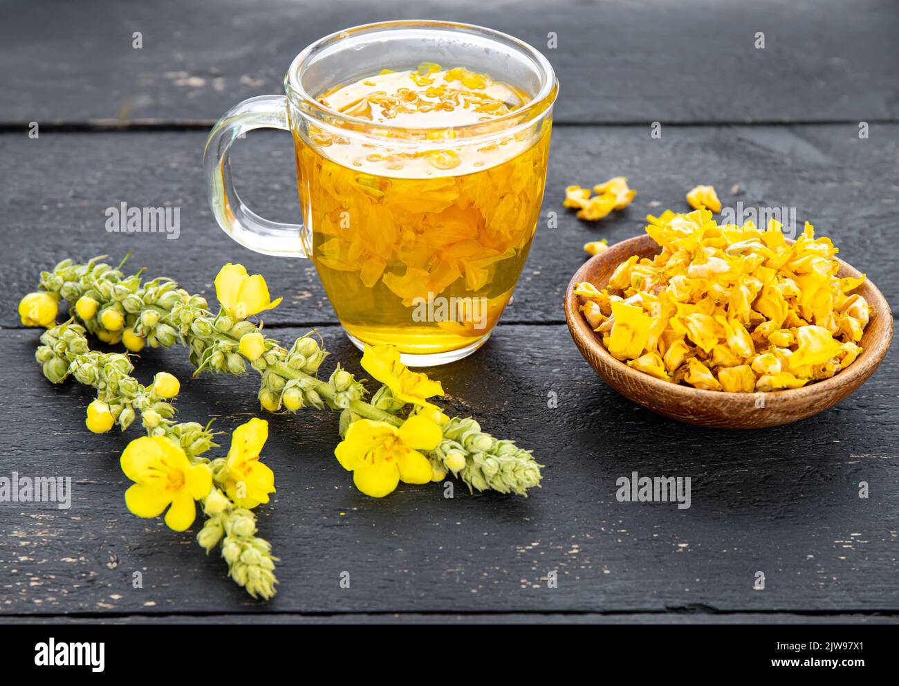 Herbal medicinal tea drink made of Verbascum thapsus, the great mullein, greater mullein or common mullein. Yellow dried flower petals. Glass cup. Stock Photo