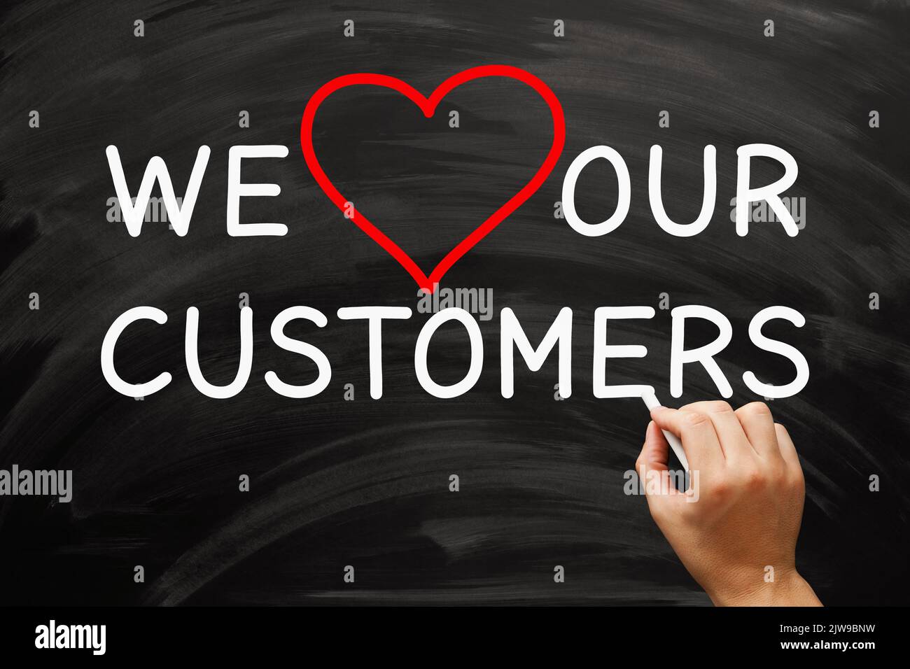 Hand writing We Love Our Customers on blackboard. Customer appreciation and satisfaction concept. Stock Photo