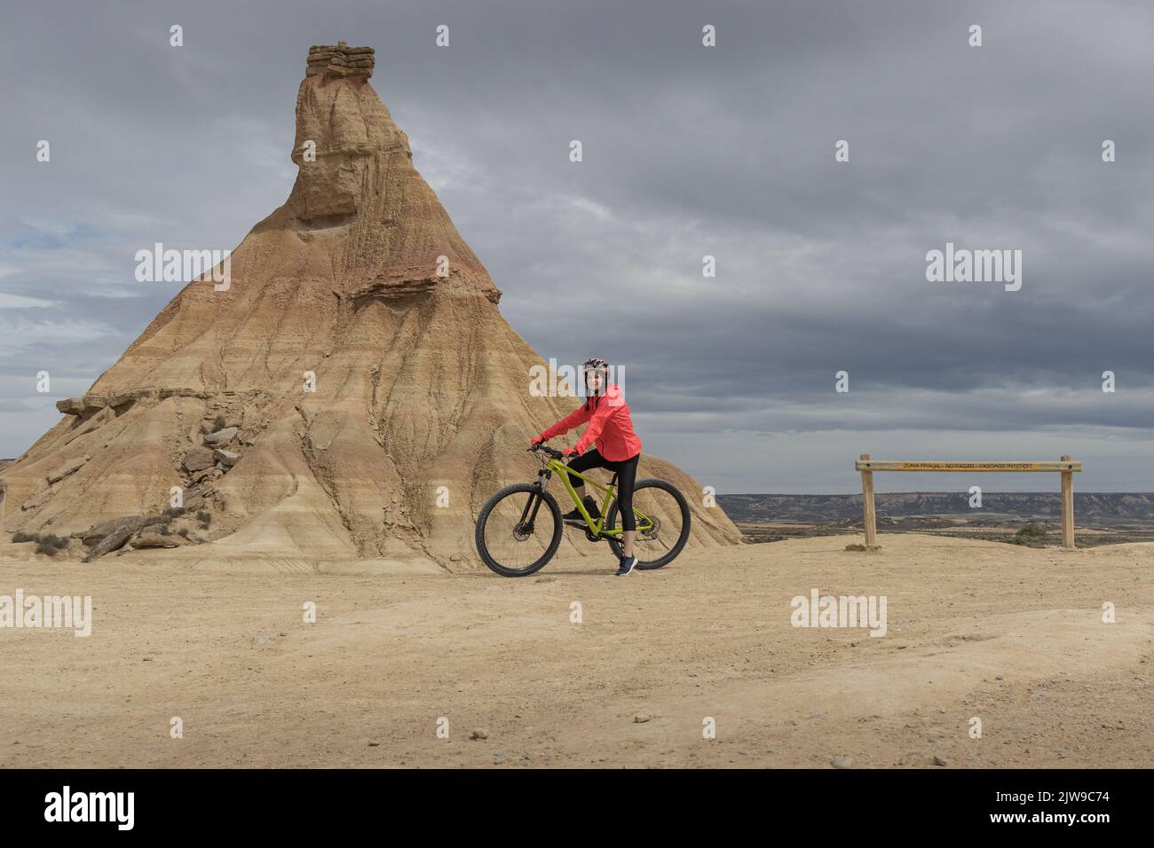 Young woman mountain bike cyclist next to Castildetierra Mountain in Badlans of Navarre (Bardenas Reales de Navarra) dessert in the middle of Spain. Stock Photo