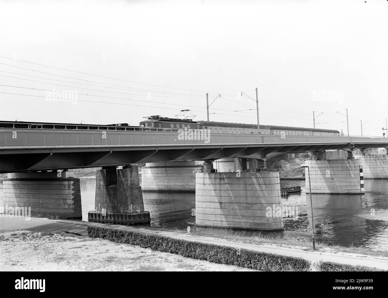 View on the new railway bridge over the Maas near Venlo with an international train drawn by an electric locomotive from the 1100 series of the N.S. Stock Photo