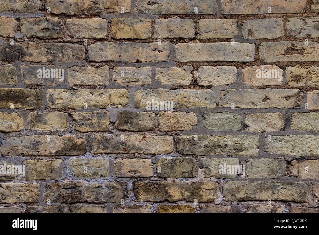 Old weathered beige brown brick wall background Stock Photo