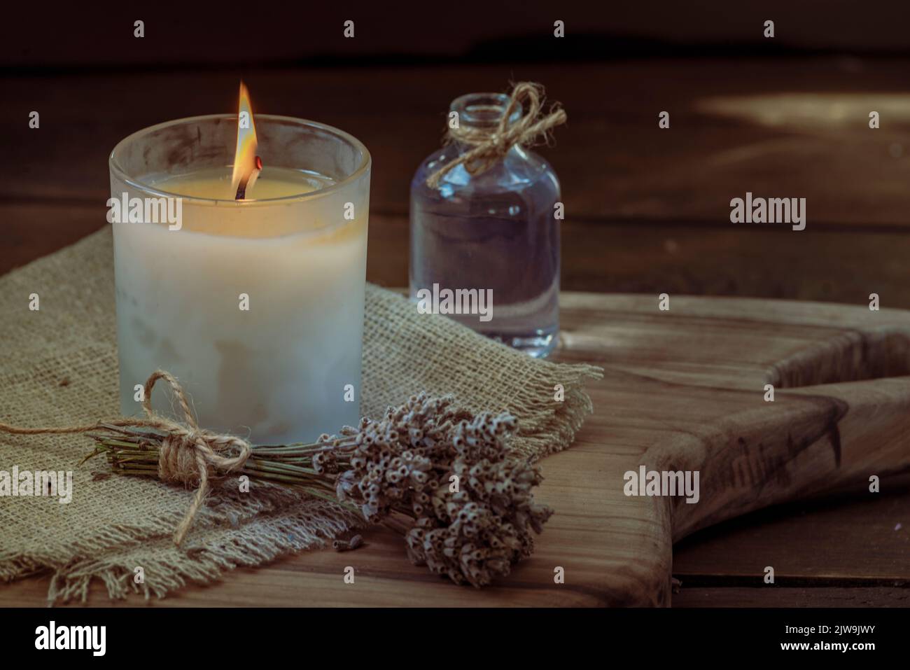 Burning white candle light on old dark wooden table background burlap ...