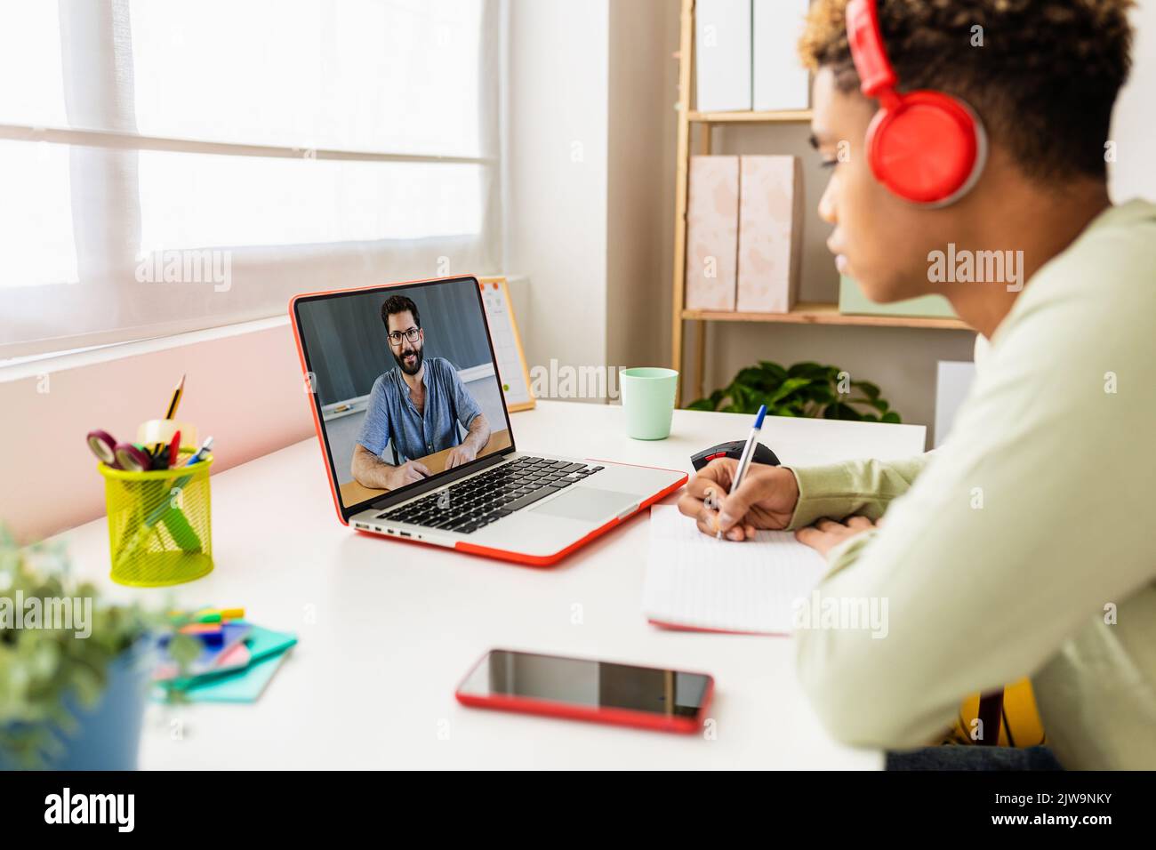 Young student studying from room watching lesson online on laptop Stock Photo