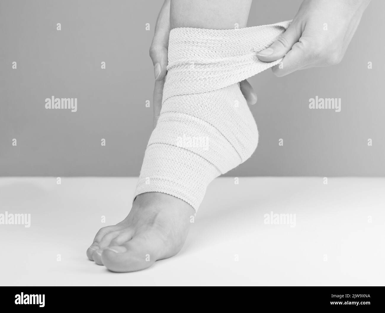 Applying elastic bandage on foot, ankle for recovery from strain, sprain, injury. High quality photo Stock Photo