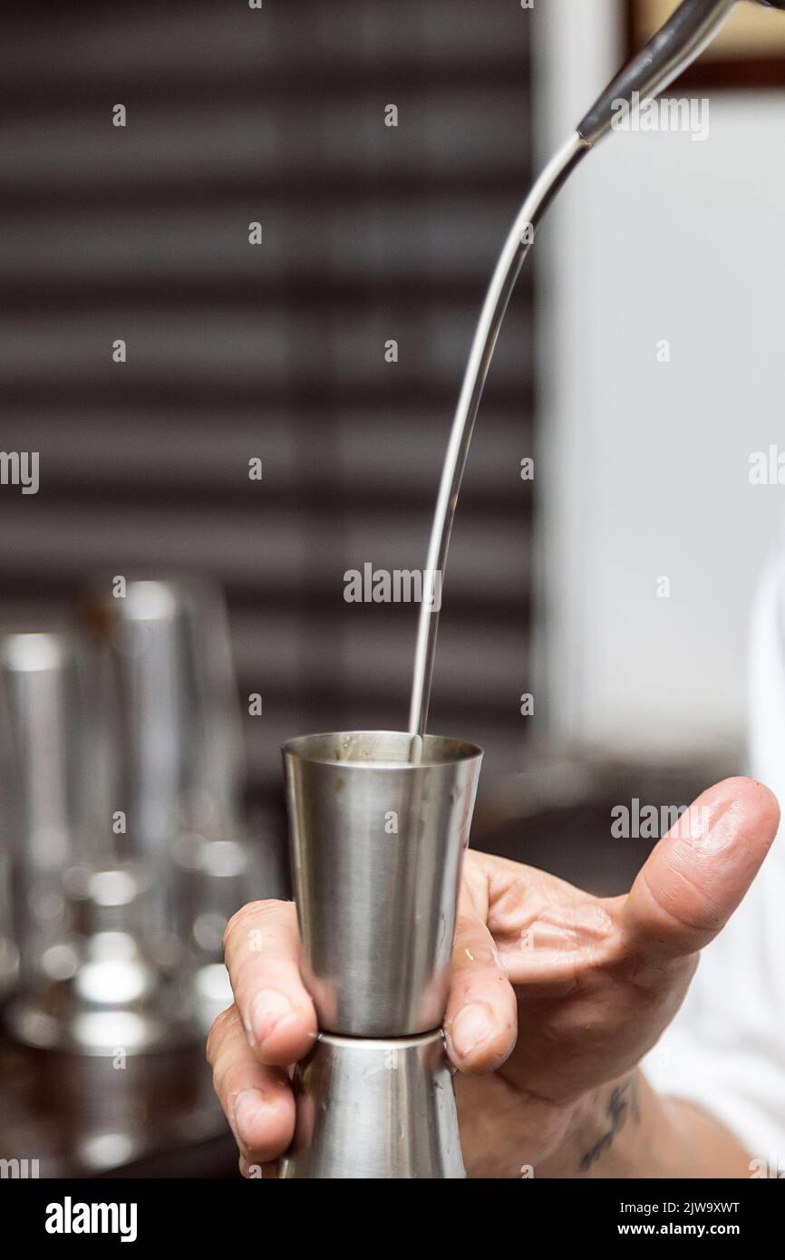 Bartender serving alcohol in a cocktail. Cocktail preparation in a night environment. It can be a hotel, a restaurant or a night club. Nightlife Stock Photo