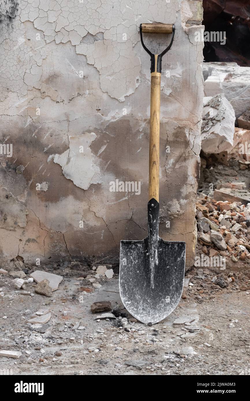 A shovel on the background of a shabby wall of an old house. Stock Photo